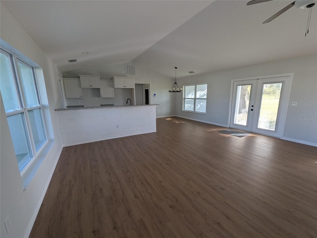 unfurnished living room with lofted ceiling, visible vents, dark wood finished floors, and baseboards