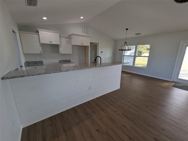 kitchen featuring light stone counters, white cabinets, visible vents, and dark wood-type flooring