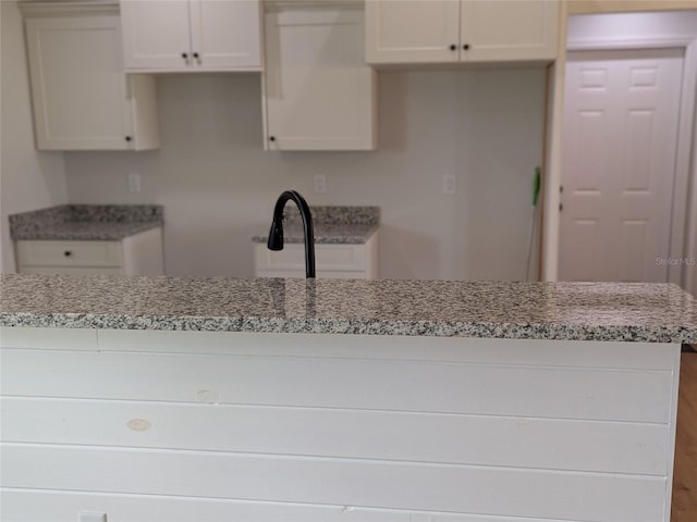 kitchen with light stone countertops and white cabinetry