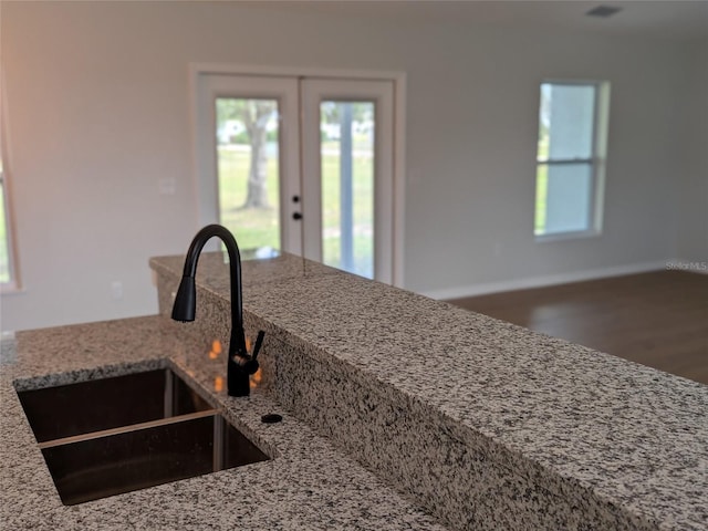 kitchen with light stone countertops, a sink, and french doors