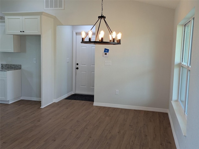 unfurnished dining area featuring dark wood-type flooring, visible vents, and baseboards