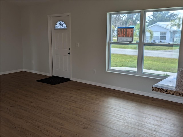 foyer entrance with dark wood-style floors and baseboards