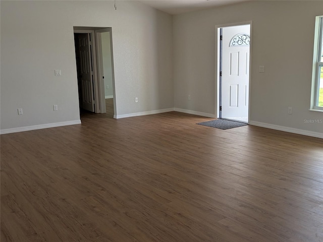 spare room with dark wood-style flooring and baseboards