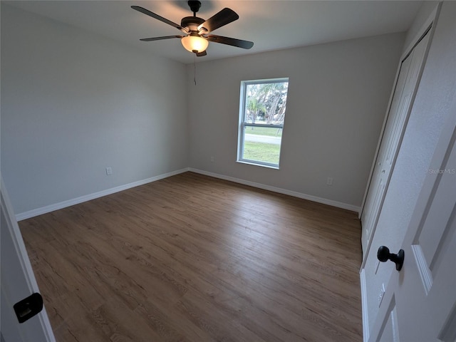 unfurnished bedroom with a closet, dark wood finished floors, a ceiling fan, and baseboards