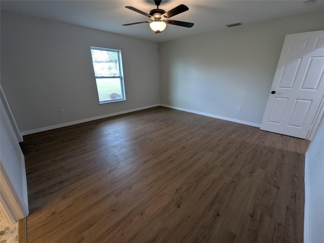 empty room featuring ceiling fan, baseboards, visible vents, and dark wood finished floors