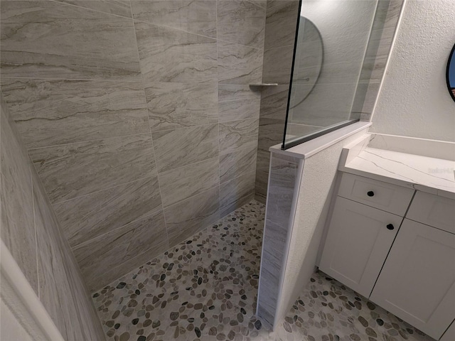 bathroom featuring a textured wall, vanity, and a walk in shower