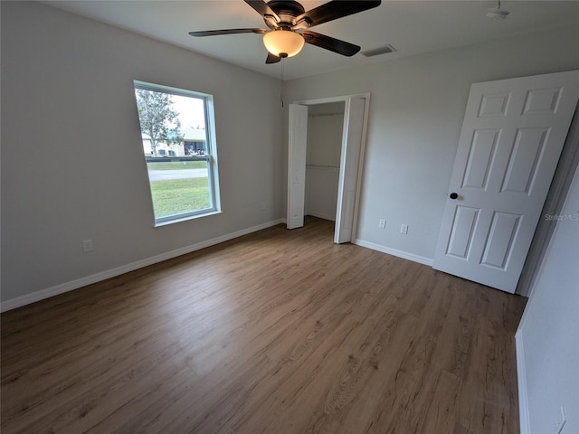 unfurnished bedroom with wood finished floors, a ceiling fan, visible vents, baseboards, and a closet