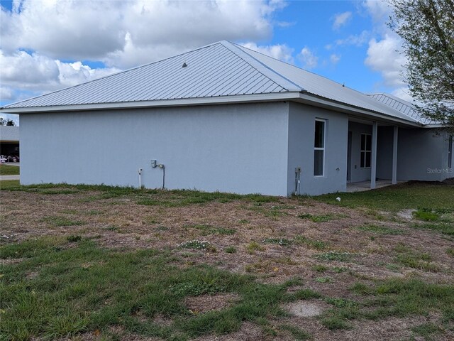 view of side of property featuring metal roof and stucco siding