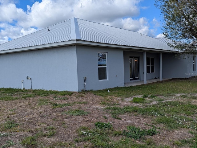 back of house featuring a patio area, metal roof, and stucco siding