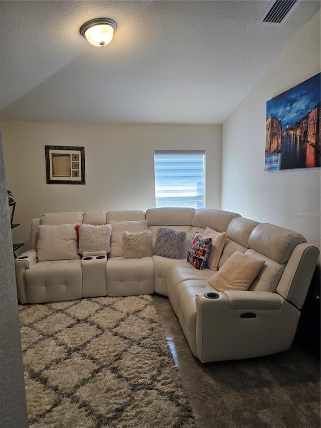 living area with visible vents, a textured ceiling, and a textured wall
