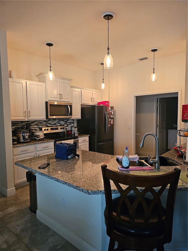 kitchen with stainless steel appliances, a kitchen breakfast bar, tasteful backsplash, and white cabinets