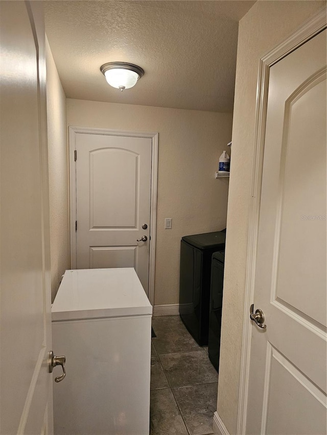laundry area with baseboards, a textured ceiling, washing machine and dryer, and laundry area