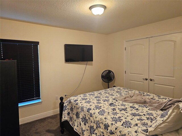 bedroom with baseboards, dark colored carpet, a closet, and a textured ceiling