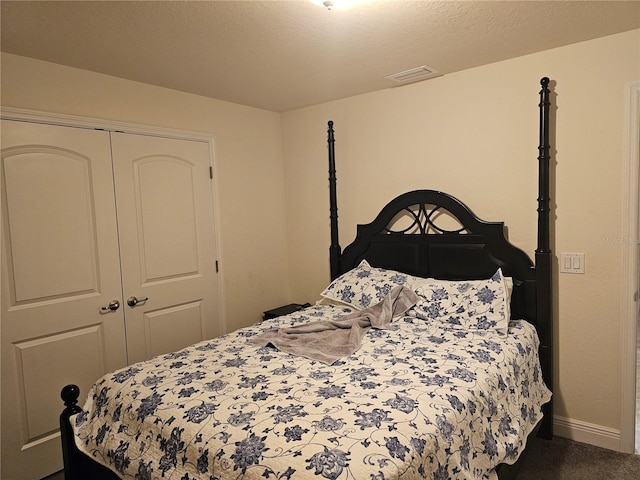 bedroom featuring visible vents, a textured ceiling, dark carpet, a closet, and baseboards
