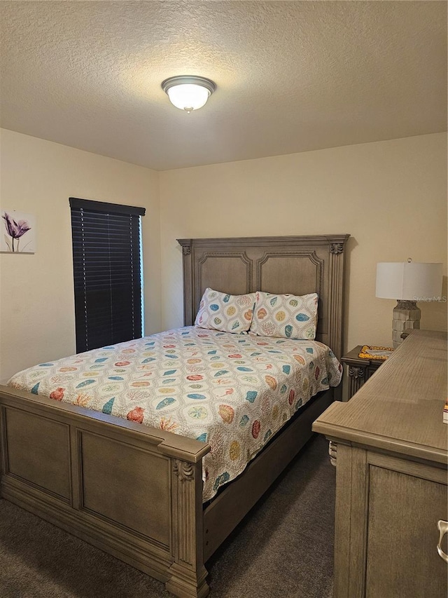 bedroom featuring a textured ceiling and dark colored carpet
