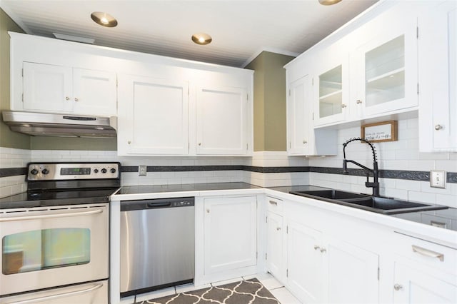 kitchen with a sink, stainless steel appliances, under cabinet range hood, white cabinetry, and backsplash