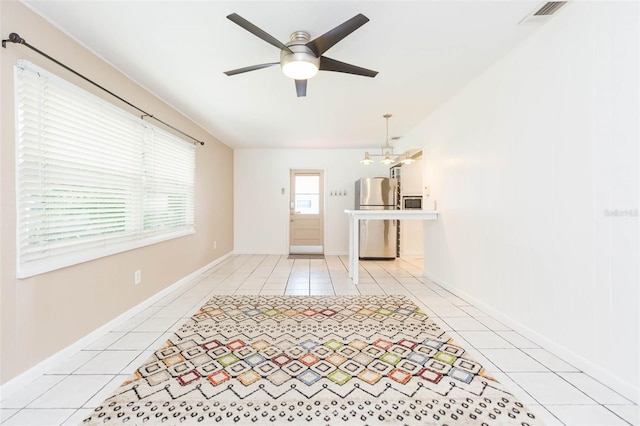 unfurnished living room with light tile patterned floors, baseboards, visible vents, and ceiling fan with notable chandelier