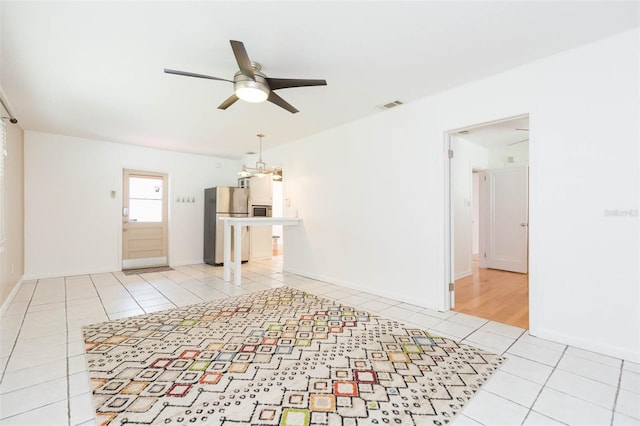 unfurnished living room featuring a ceiling fan, visible vents, baseboards, and tile patterned floors