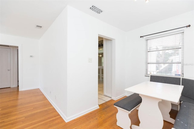 dining space with light wood finished floors, visible vents, and baseboards