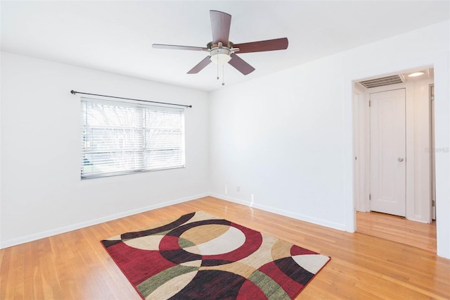 unfurnished room with baseboards, visible vents, ceiling fan, and light wood finished floors