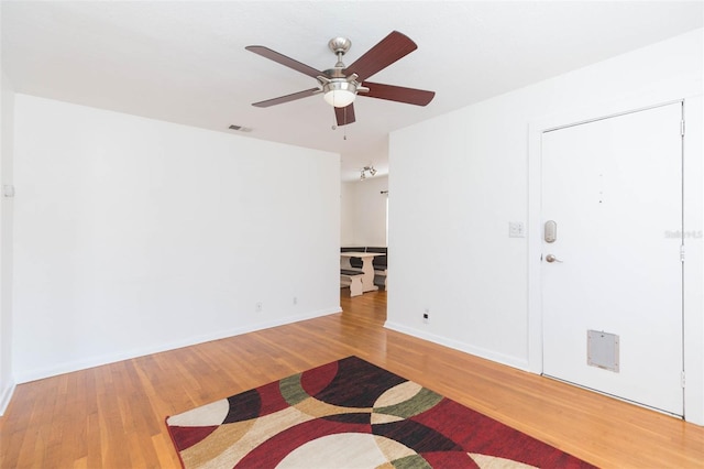 empty room featuring visible vents, ceiling fan, baseboards, and wood finished floors