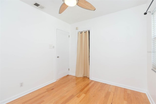 spare room with ceiling fan, light wood-type flooring, visible vents, and baseboards