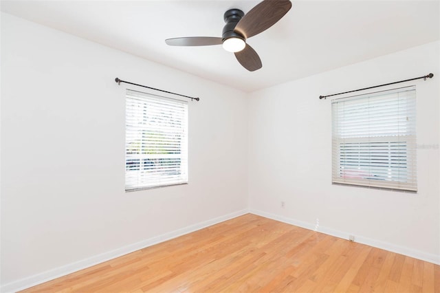 spare room featuring ceiling fan, light wood-type flooring, and baseboards