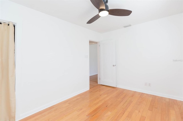 spare room featuring baseboards, ceiling fan, visible vents, and light wood finished floors