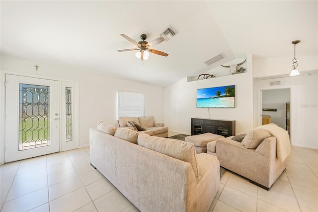 living room featuring lofted ceiling, light tile patterned floors, and visible vents