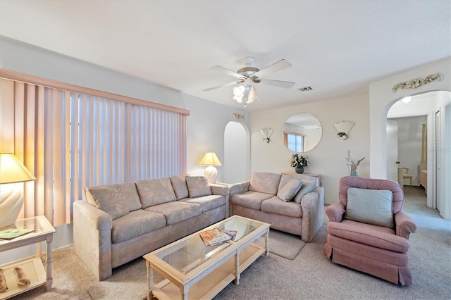 carpeted living room featuring a ceiling fan, visible vents, and arched walkways