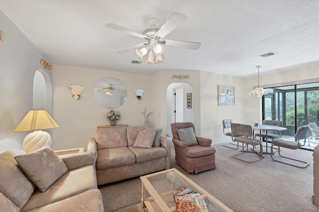 living area featuring arched walkways, visible vents, ceiling fan, and carpet floors