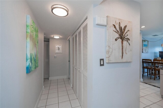 corridor with baseboards and light tile patterned flooring