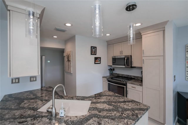 kitchen with visible vents, appliances with stainless steel finishes, dark stone countertops, decorative light fixtures, and a sink