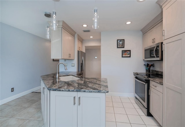 kitchen featuring light tile patterned flooring, stainless steel appliances, a sink, visible vents, and dark stone counters