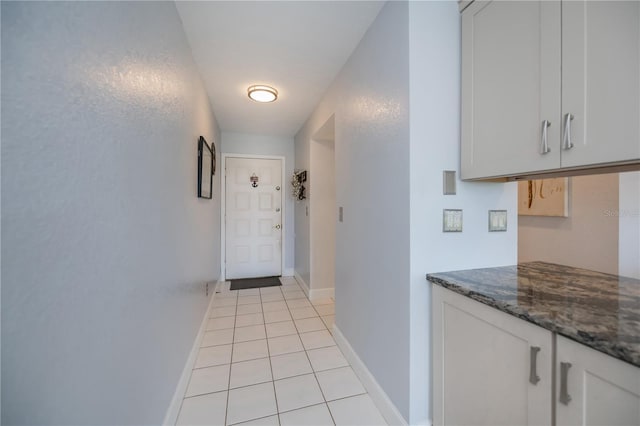 doorway featuring light tile patterned flooring and baseboards