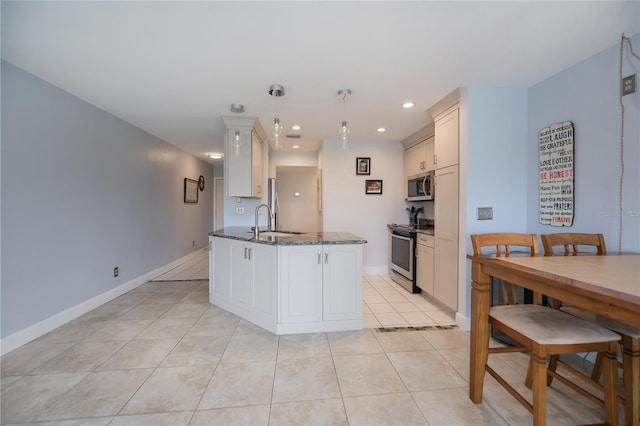 kitchen with light tile patterned floors, baseboards, dark stone counters, stainless steel appliances, and a sink