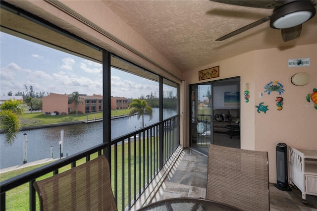 sunroom / solarium featuring ceiling fan and a water view