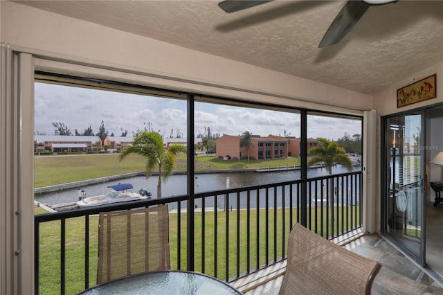 sunroom / solarium featuring a water view, a residential view, and a ceiling fan