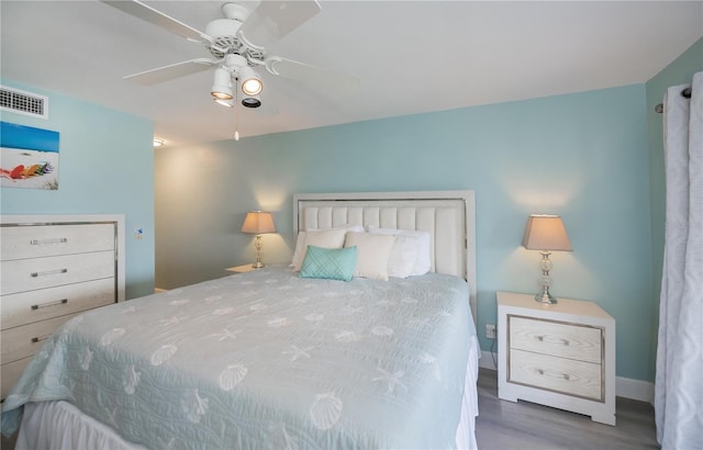 bedroom featuring ceiling fan, visible vents, and wood finished floors