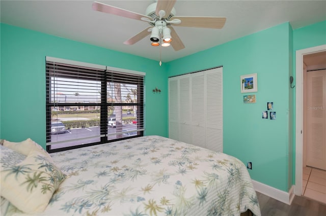 bedroom featuring ceiling fan, a closet, wood finished floors, and baseboards