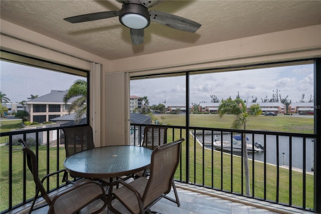 sunroom with ceiling fan and a residential view