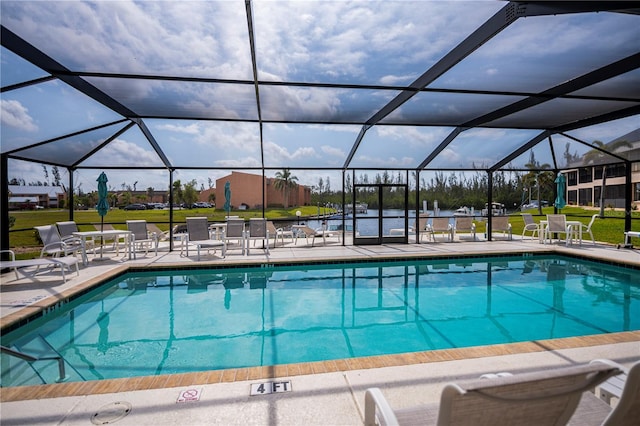 pool featuring glass enclosure, a patio, and a lawn