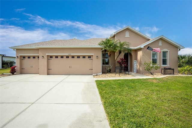 ranch-style home featuring concrete driveway, a front lawn, an attached garage, and stucco siding