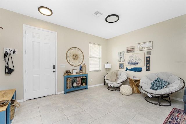 living area with light tile patterned floors, visible vents, and baseboards