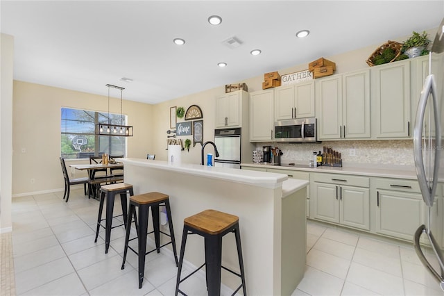 kitchen featuring stainless steel appliances, tasteful backsplash, visible vents, light tile patterned flooring, and a kitchen bar