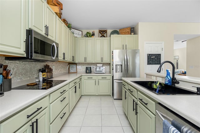 kitchen featuring stainless steel appliances, light countertops, a sink, and green cabinets