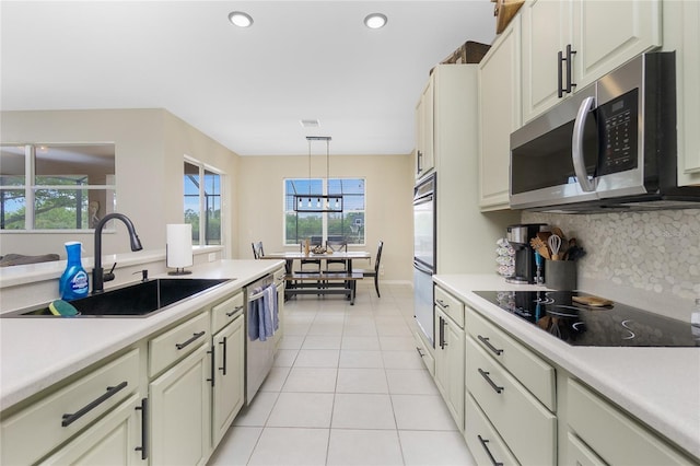 kitchen with light tile patterned flooring, stainless steel appliances, a sink, light countertops, and decorative backsplash