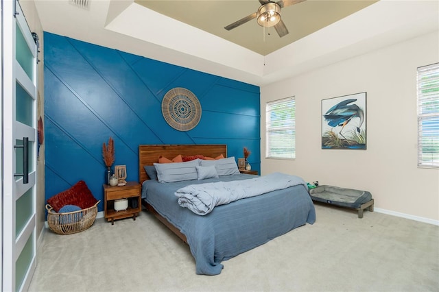 bedroom featuring carpet floors, baseboards, a tray ceiling, and a ceiling fan