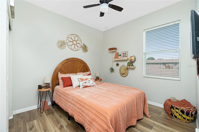 bedroom with a ceiling fan, baseboards, and wood finished floors