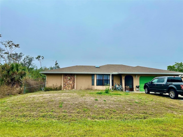 ranch-style home featuring a garage, a front yard, fence, and stucco siding